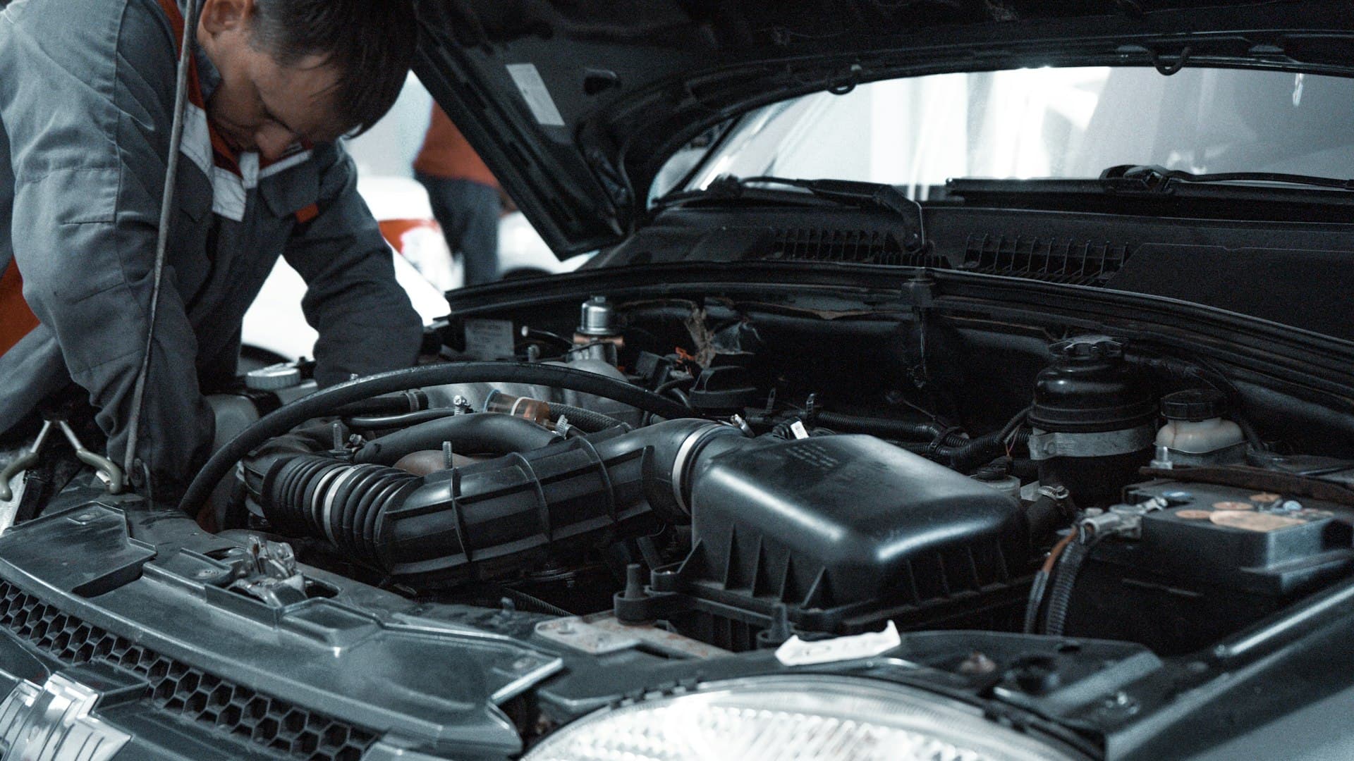 Mechanic diagnosing and repairing a car engine in the workshop